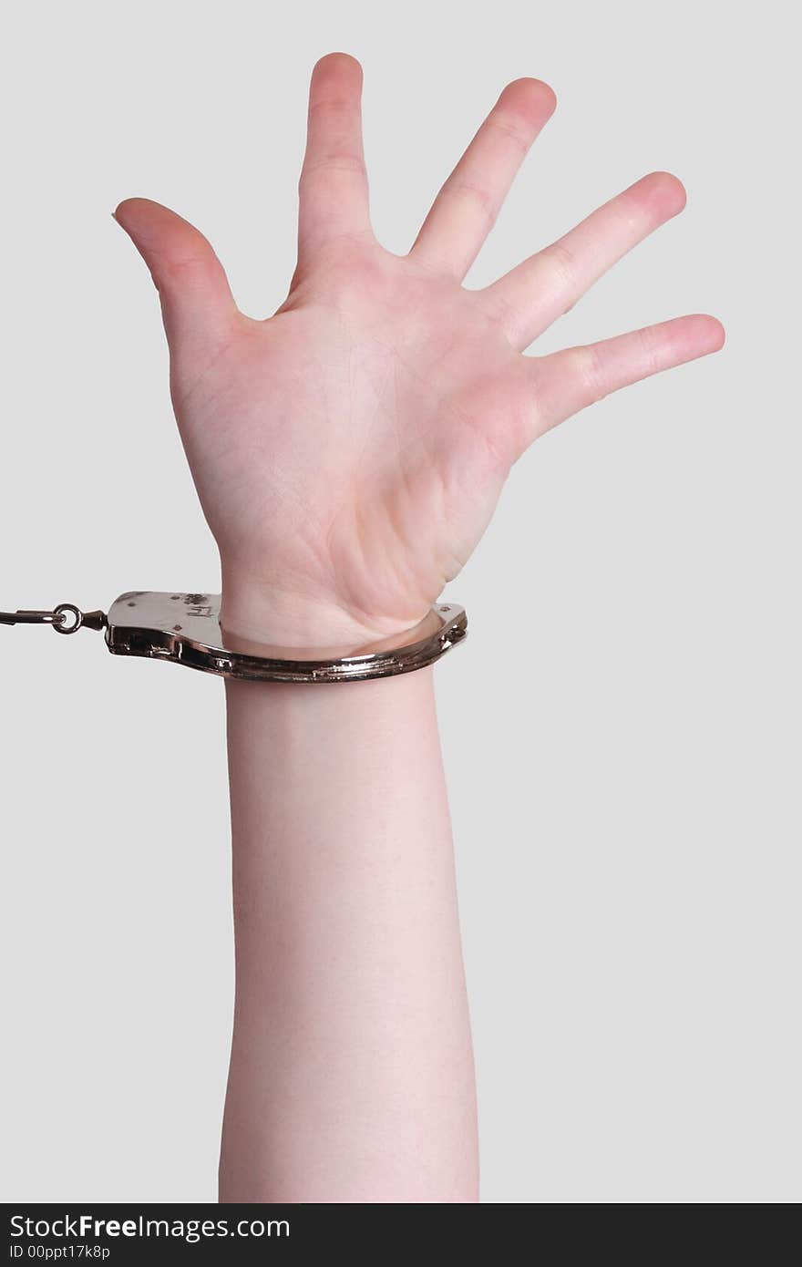 Picture of a female arm with handcuffs on gray background. Picture of a female arm with handcuffs on gray background.