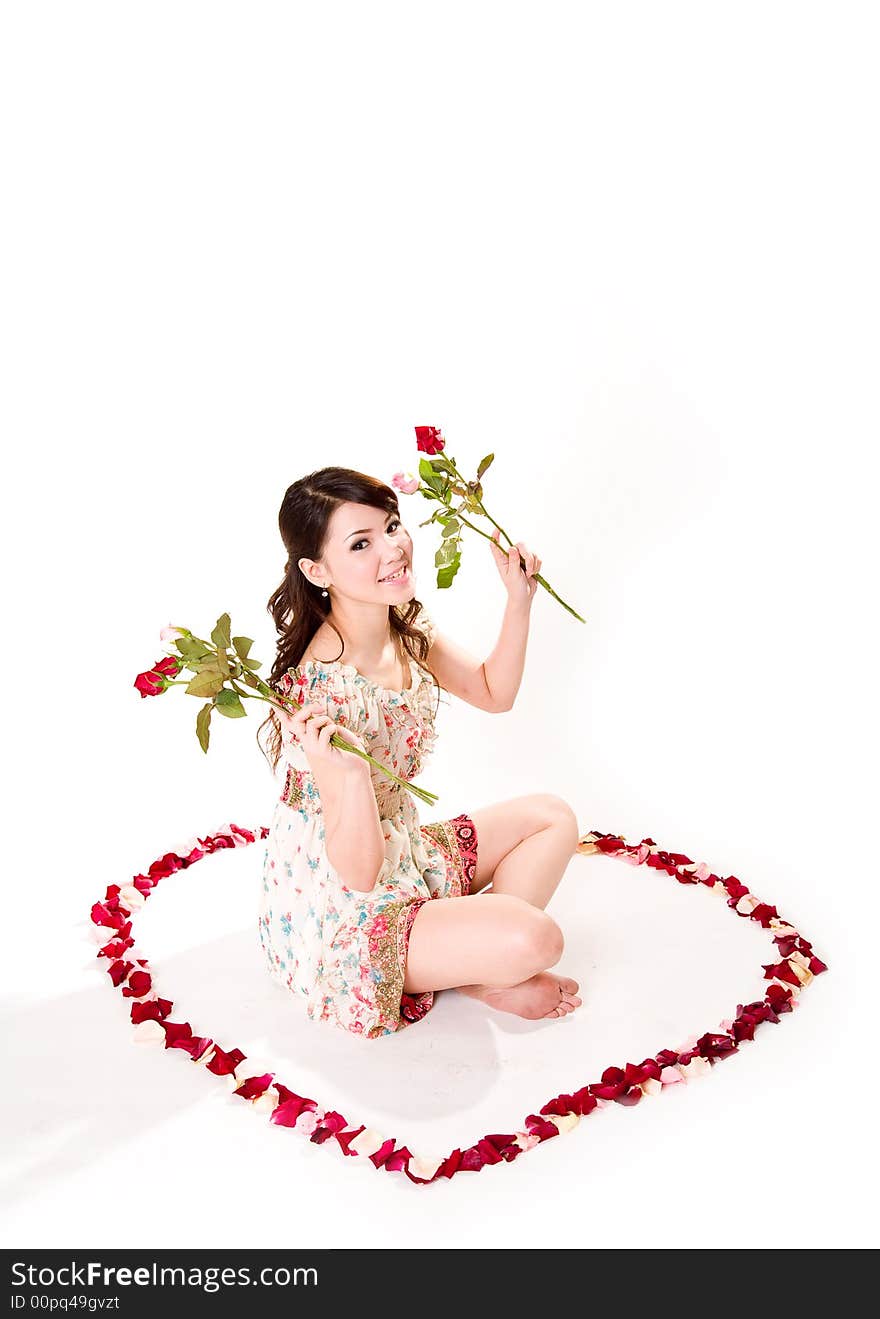 Young woman with roses sitting inside a rose petal heart shape. Young woman with roses sitting inside a rose petal heart shape