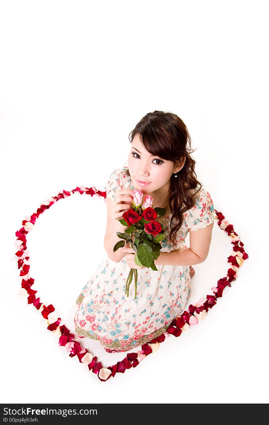 Young woman with roses sitting inside a rose petal heart shape. Young woman with roses sitting inside a rose petal heart shape