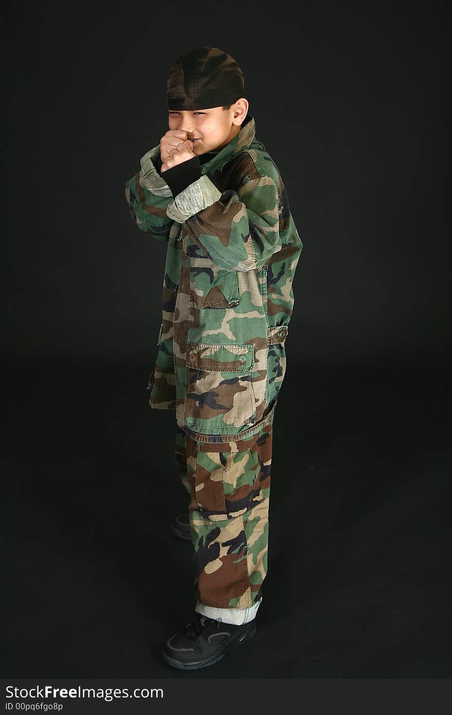 Handsome nine year old Filipino boy in camo fatigues with fist up.