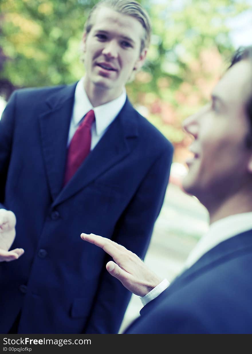 Two businessmen standing talking outdoors. Two businessmen standing talking outdoors