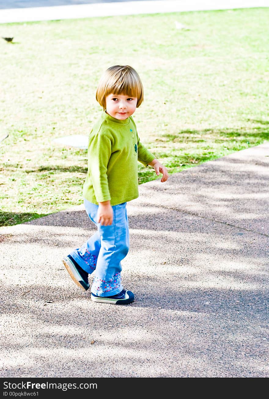 A three year old girl in the park with her family. A three year old girl in the park with her family.