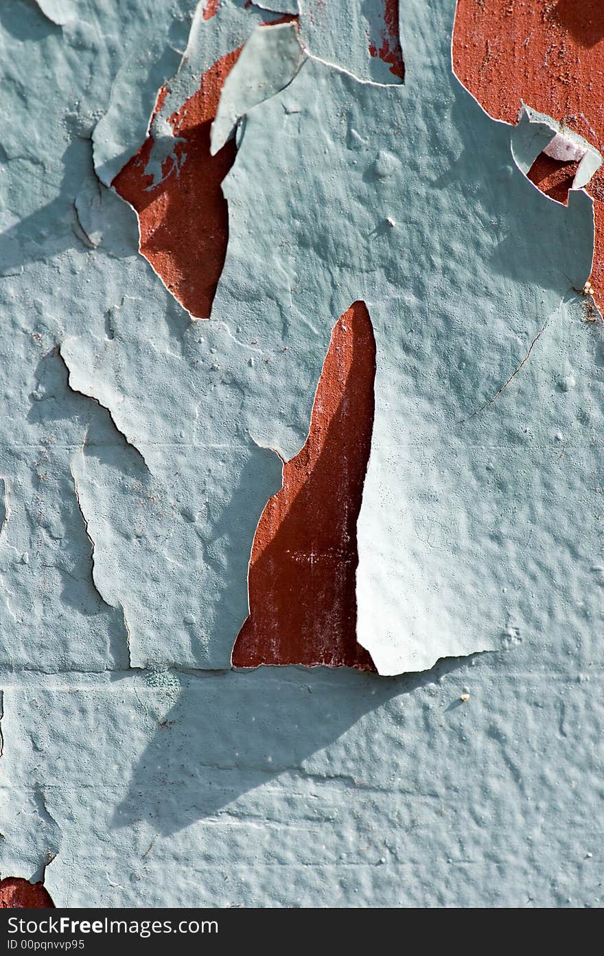 Close up of a red wall with green colored paint that is cracking. Close up of a red wall with green colored paint that is cracking