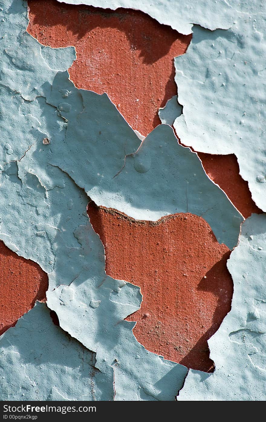 Close up of a red wall with green colored paint that is cracking. Close up of a red wall with green colored paint that is cracking