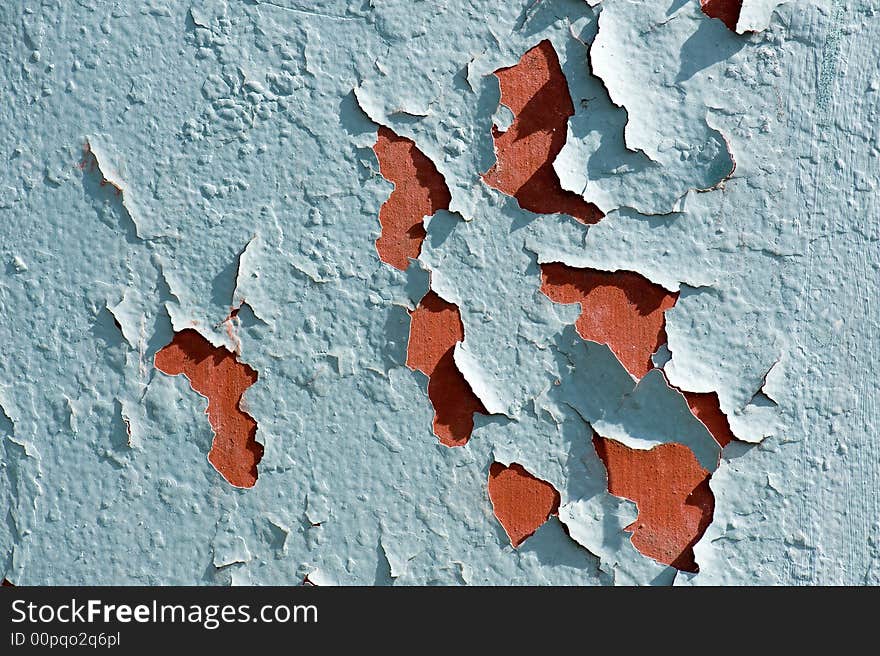 Close up of a red wall with green colored paint that is cracking. Close up of a red wall with green colored paint that is cracking