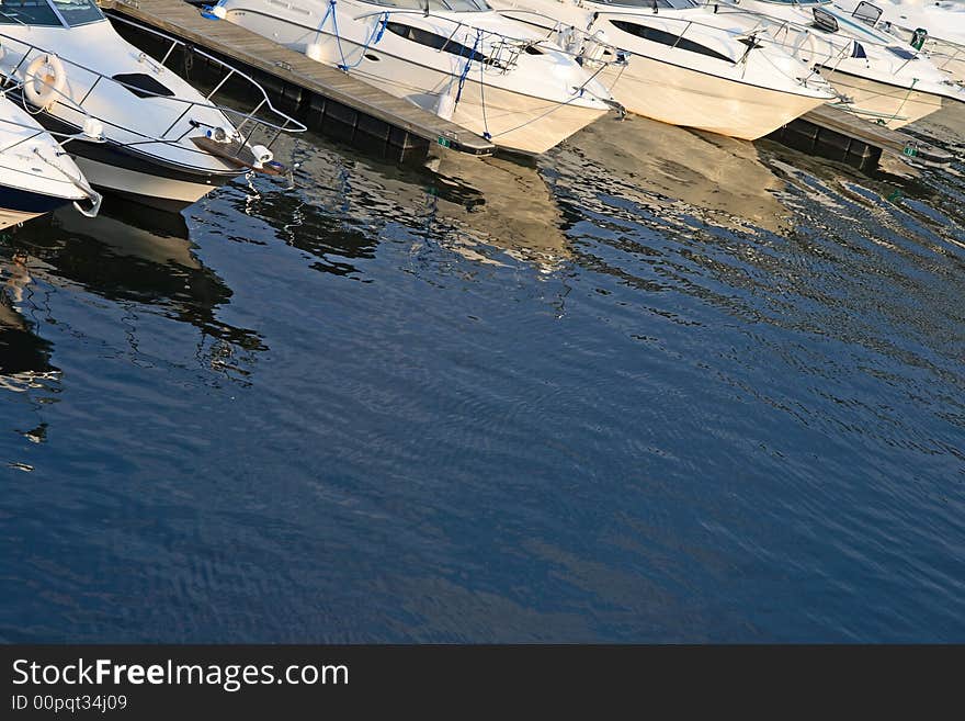 Motorboats in a harbor reflecting in water. Motorboats in a harbor reflecting in water.