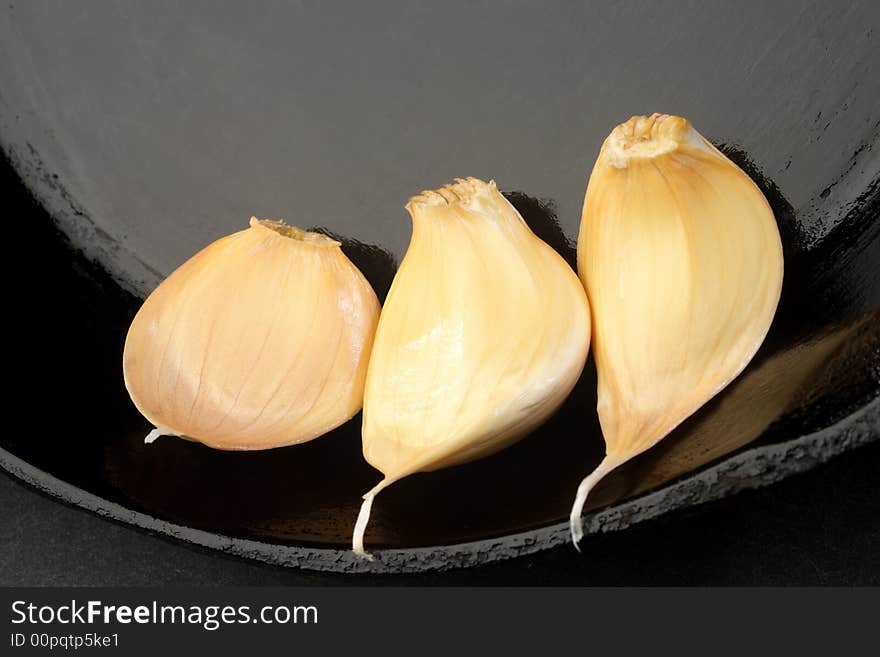 Three Cloves of garlic in a cast iron skillet.