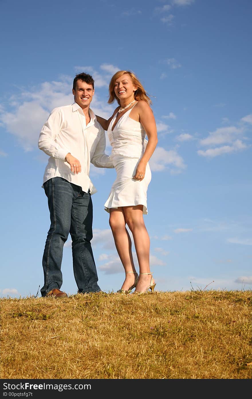 The couple stand on meadow