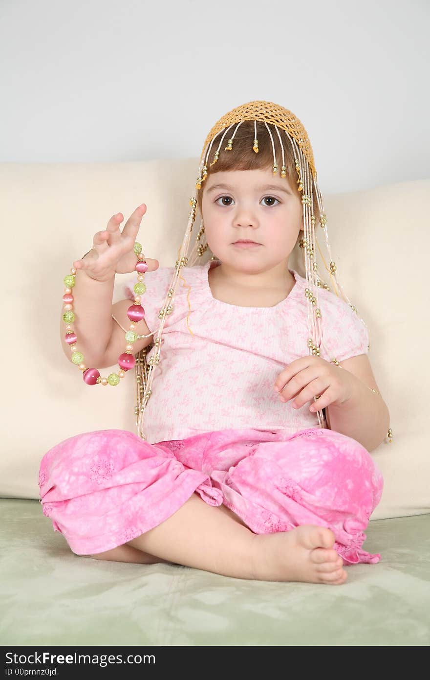 Girl on  sofa in  eastern hat with beads. Girl on  sofa in  eastern hat with beads