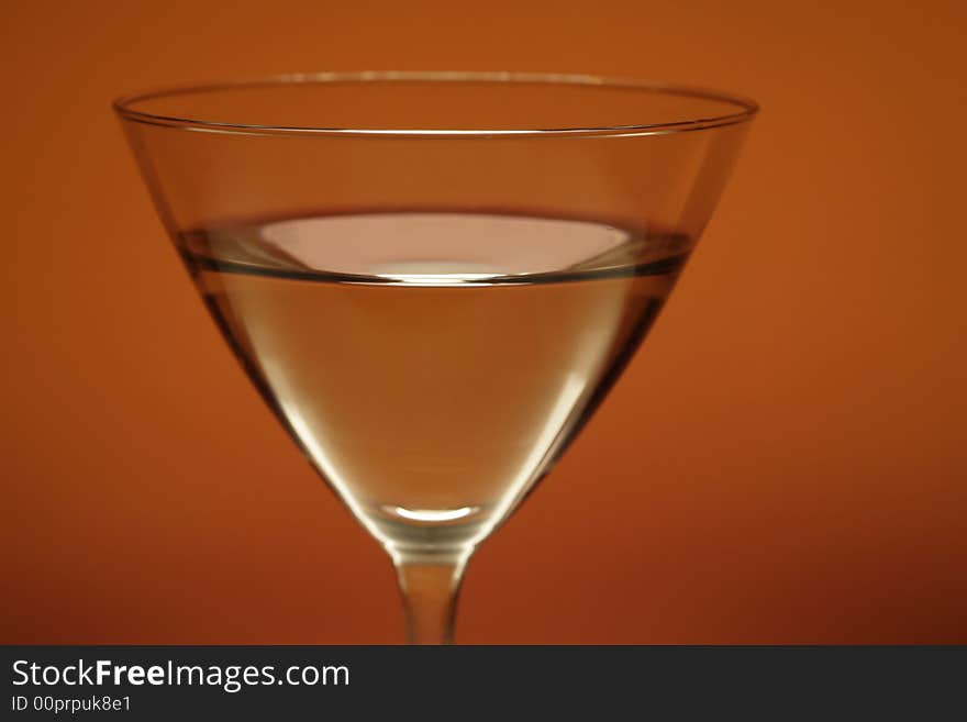 Cocktail glass with water on orange background