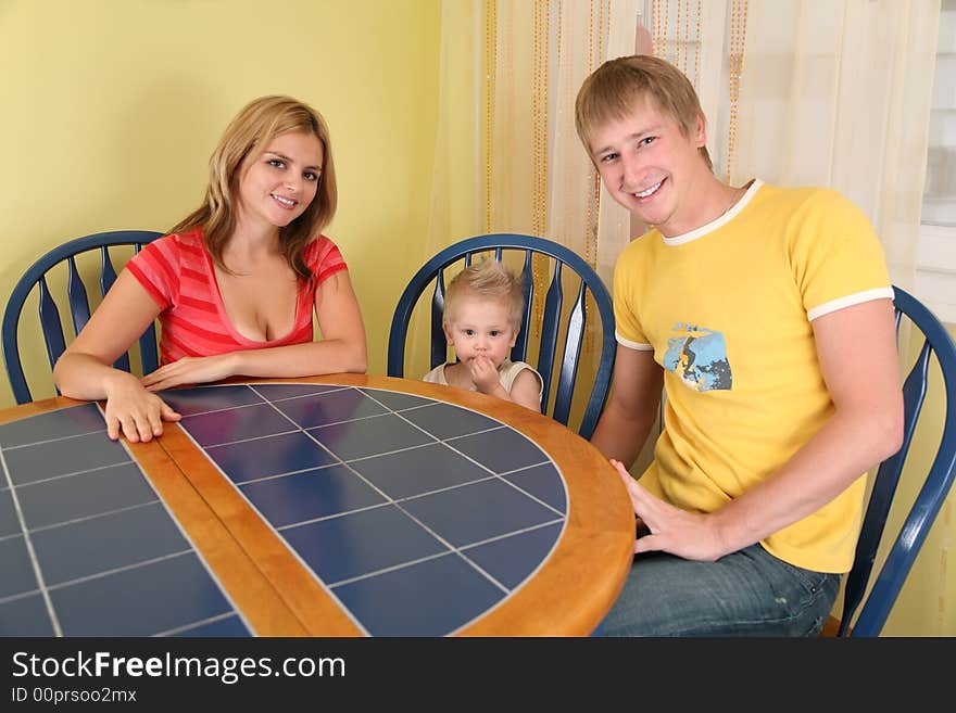 Parents with child sit at table in room