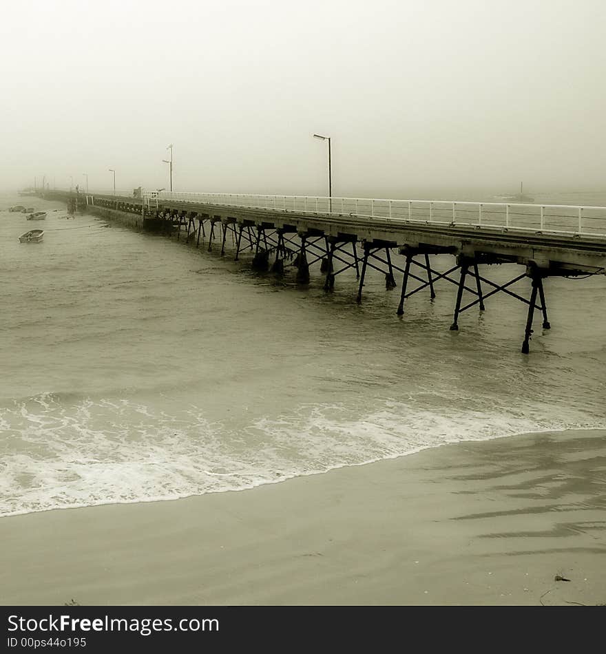 A pier disappearing into the fog in black and white. A pier disappearing into the fog in black and white