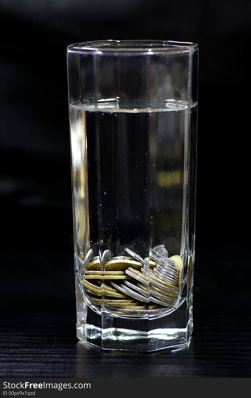 Coin in the container with the water against the black background. Coin in the container with the water against the black background