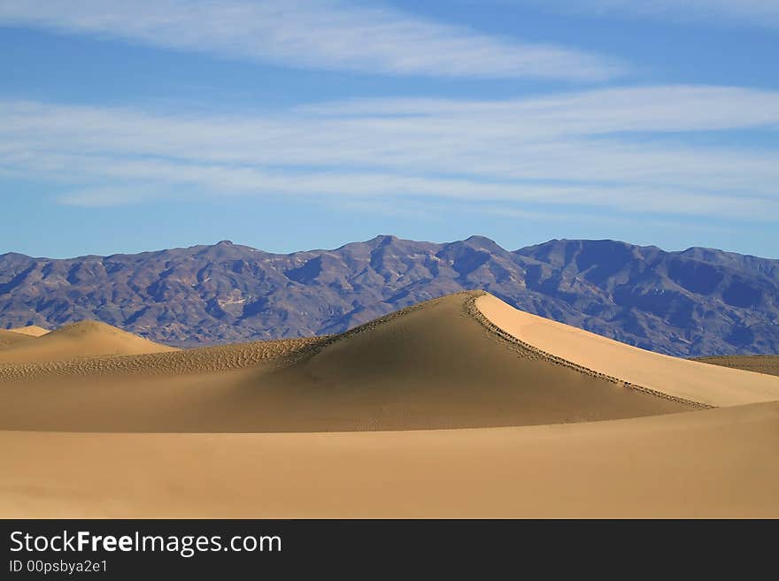 Dry desert sand dunes with mountains in the background. Dry desert sand dunes with mountains in the background