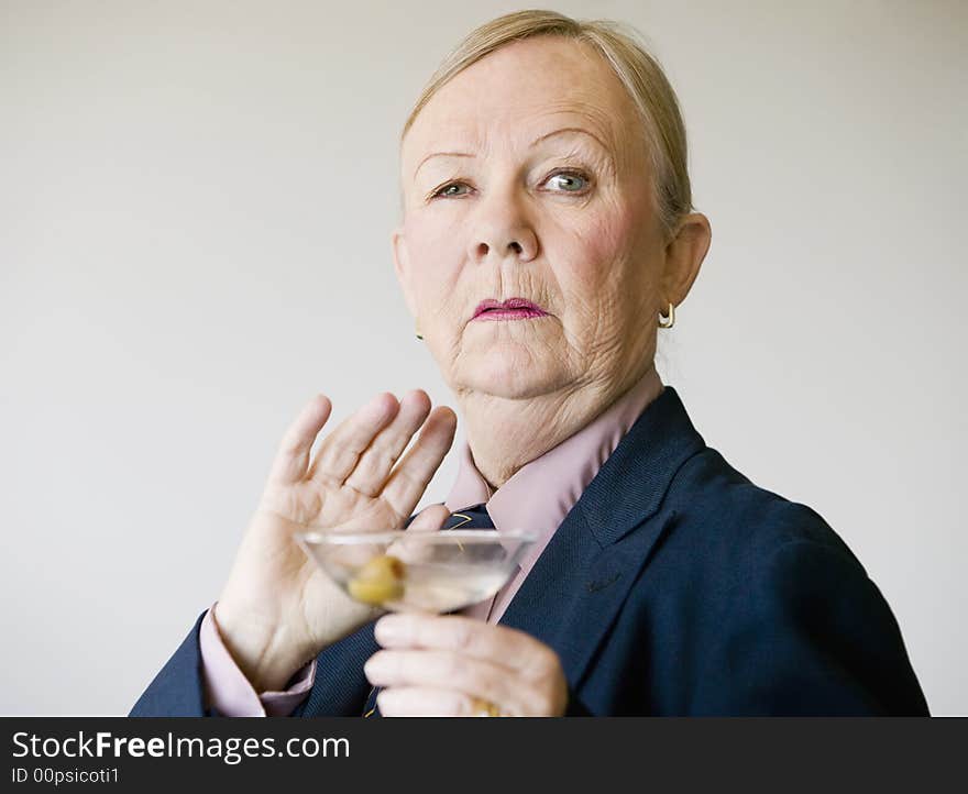 Dramatic senior woman in a man's suit holding a Martini. Dramatic senior woman in a man's suit holding a Martini.
