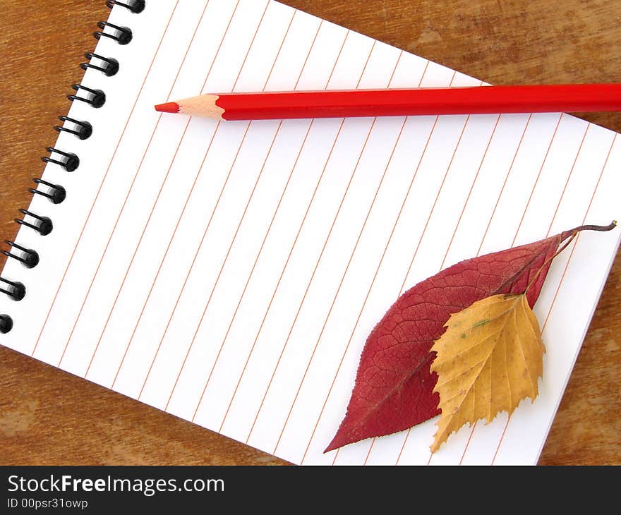 Spiral notepad with red pencil and colorful autumnal leaves. Spiral notepad with red pencil and colorful autumnal leaves