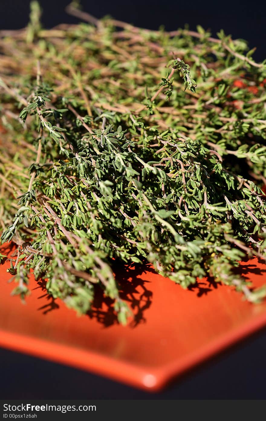 Freshly picked thyme sprigs on an orange plate. Freshly picked thyme sprigs on an orange plate