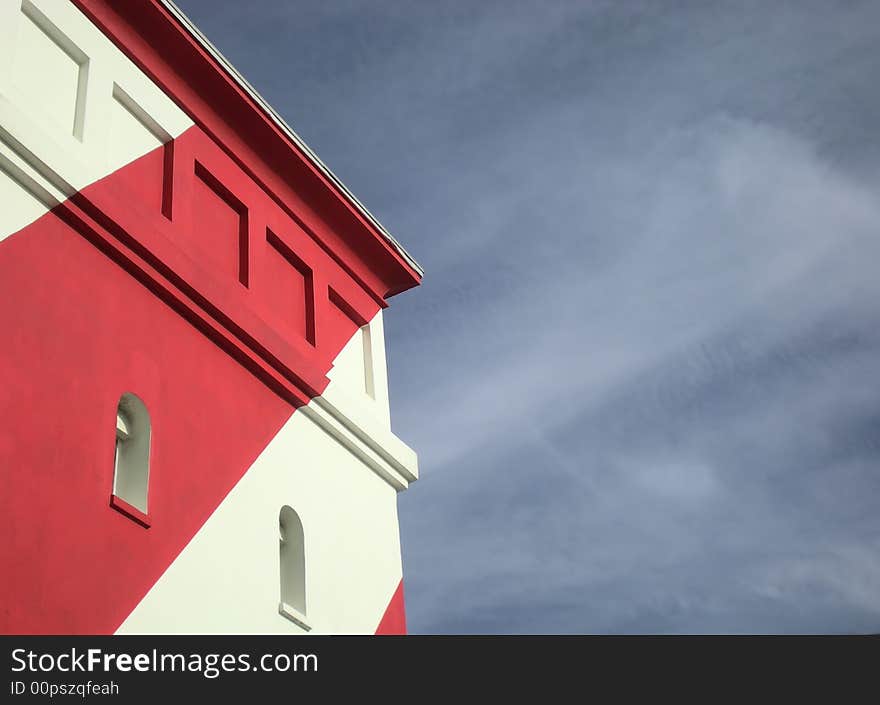 Part of a colourful red and white lighthouse on the shore. Part of a colourful red and white lighthouse on the shore