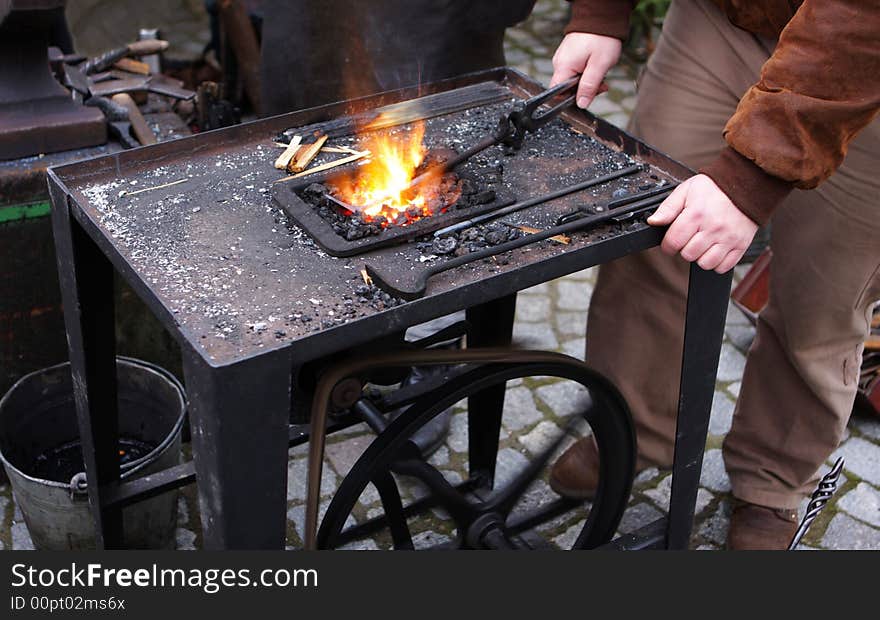 Smith standing beside smith´s forge with fire and smith´s tools. Smith standing beside smith´s forge with fire and smith´s tools