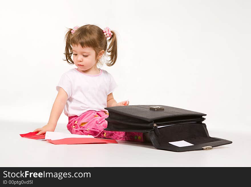 Cute little girl arranging papers in a briefcase. Cute little girl arranging papers in a briefcase