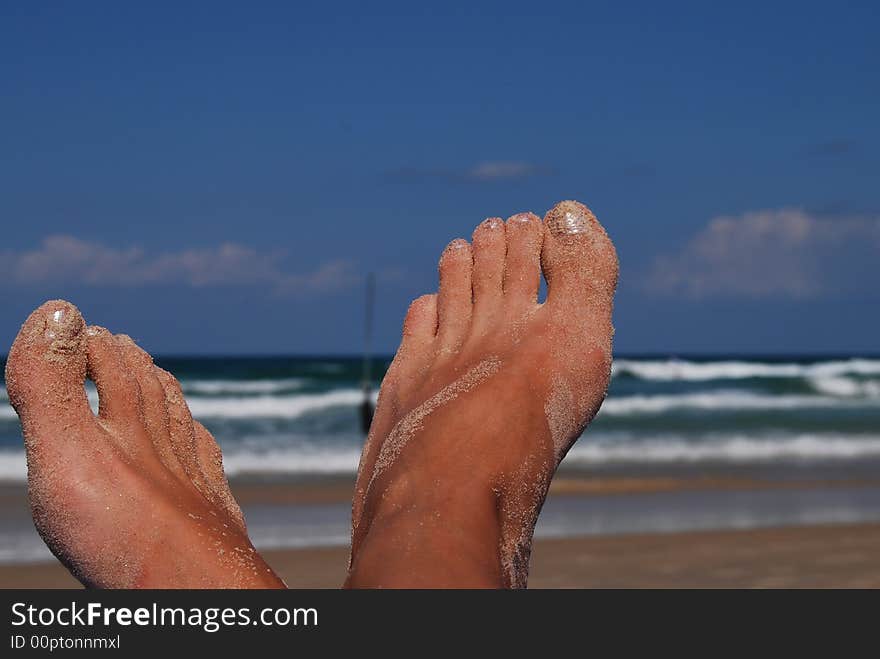 Female feet on back-ground sea in sand