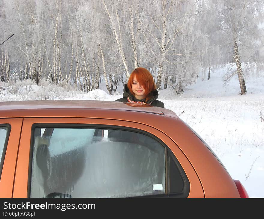 Red-haired girl and orange car at winter day