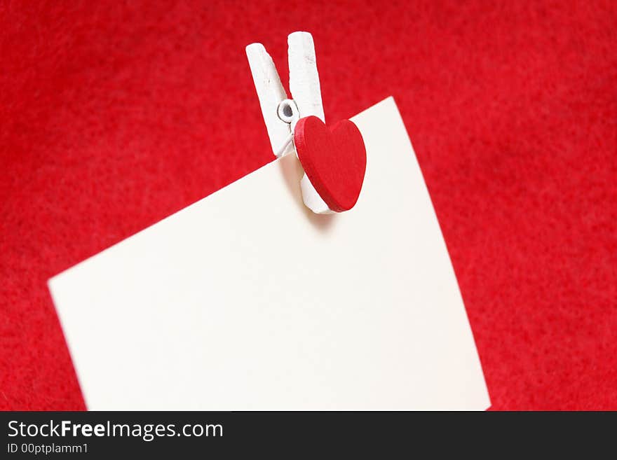 A clip with a heart holding a white sheet of paper. A clip with a heart holding a white sheet of paper