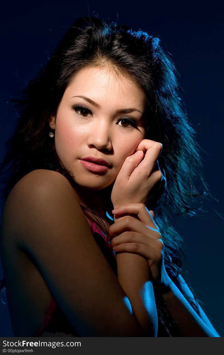 Young woman with a moody sensual alluring look under blue lighting