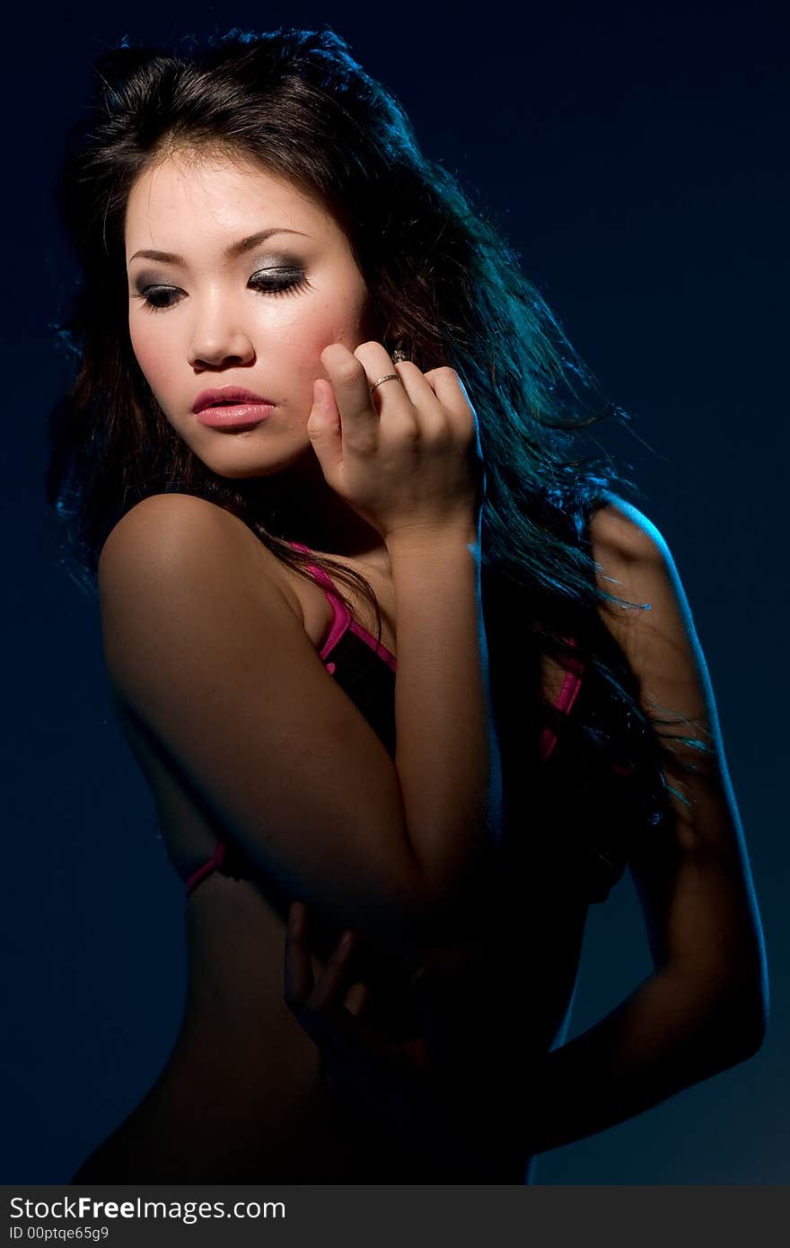 Young woman with a moody sensual alluring look under blue lighting