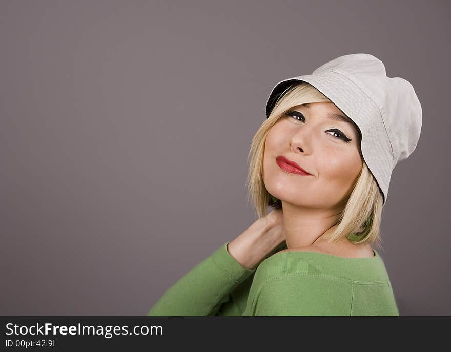 A blonde model with white hat and hand on neck. A blonde model with white hat and hand on neck