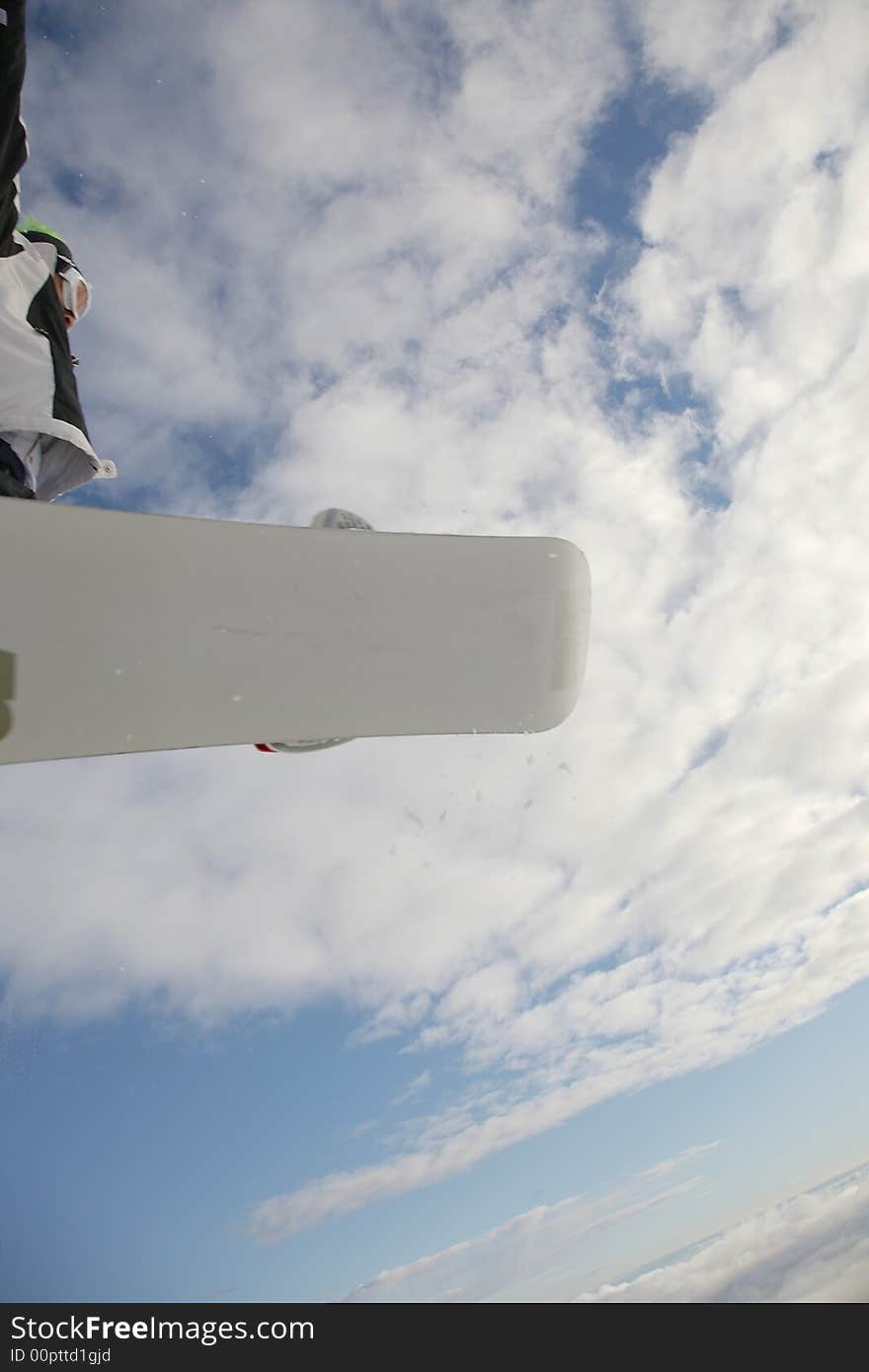 Snowboarder launching off a jump; vertical orientation, afternoon light.