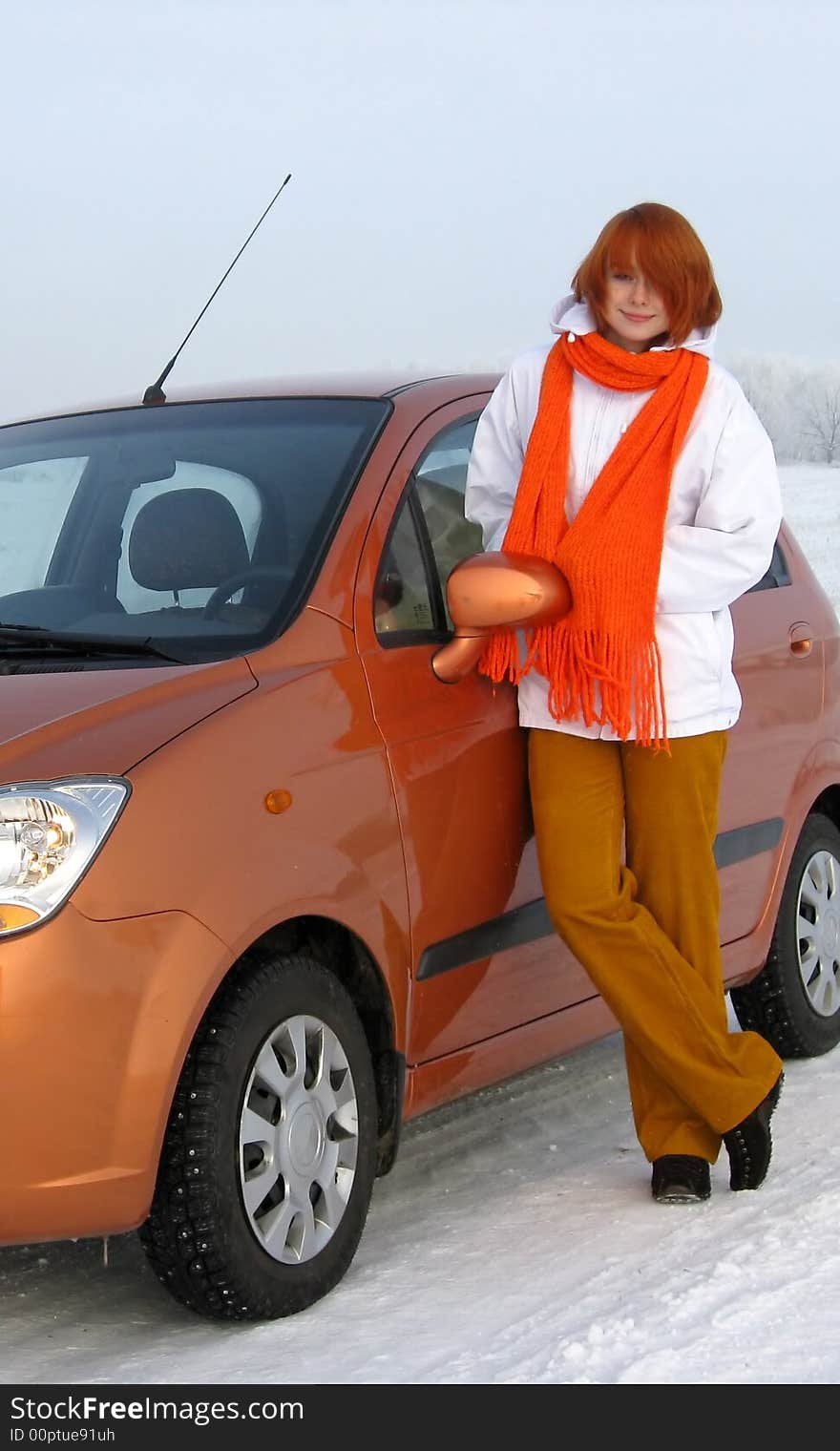 Red-haired girl and orange car on winter road