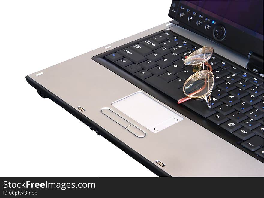 Laptop computer closeup with eyeglasses sitting on keyboard.