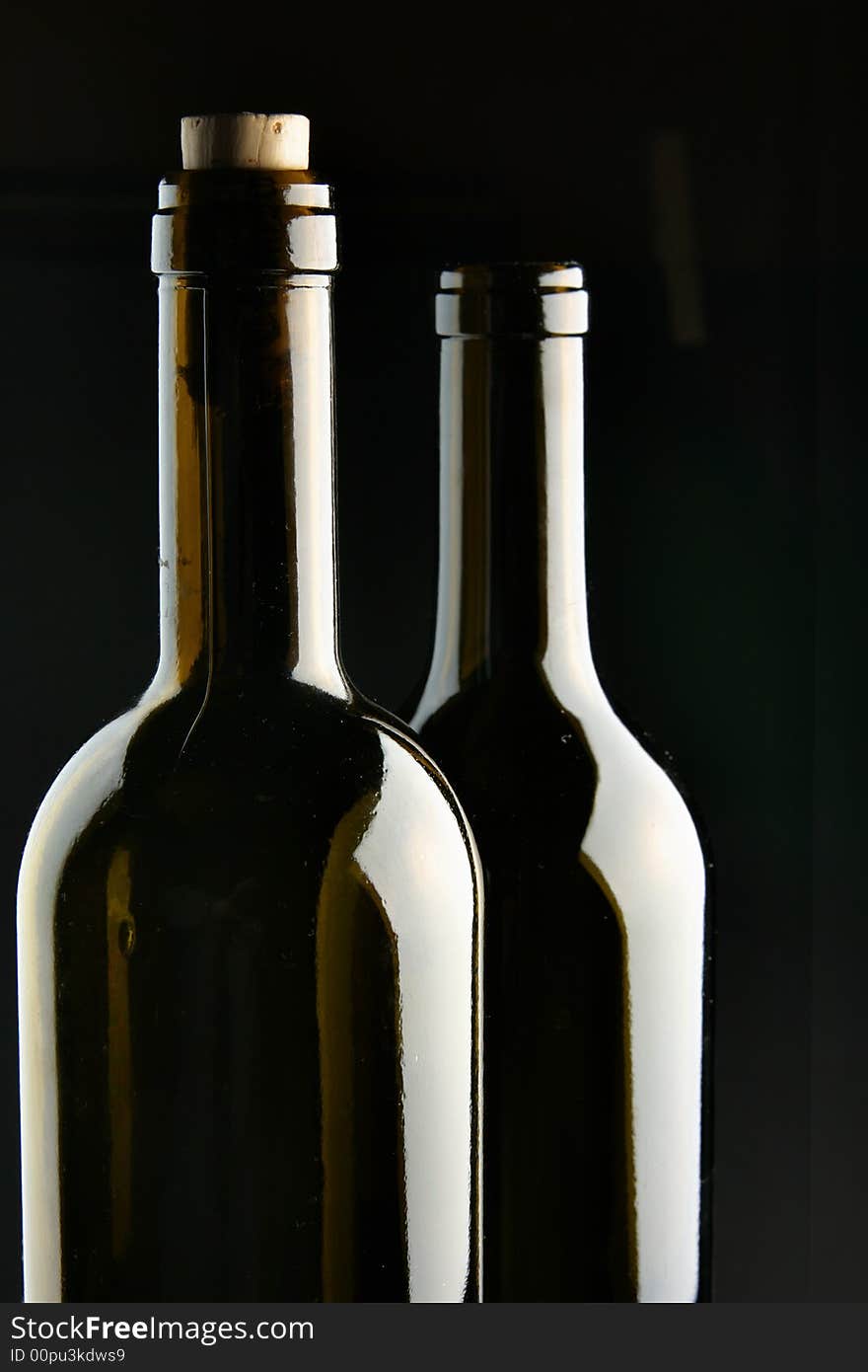 Necks of two bottles over black background