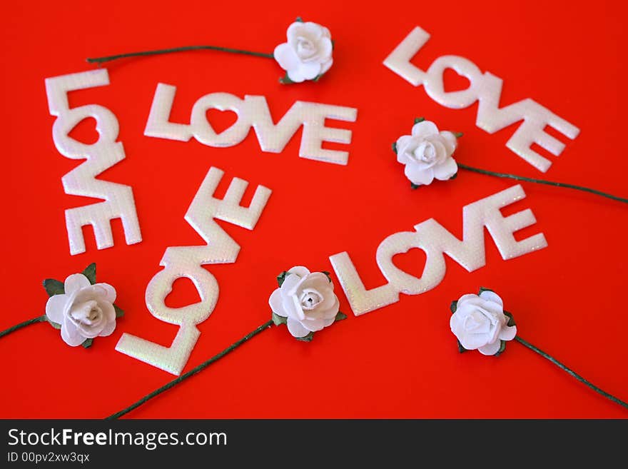 The word love on a red background with small white roses. The word love on a red background with small white roses