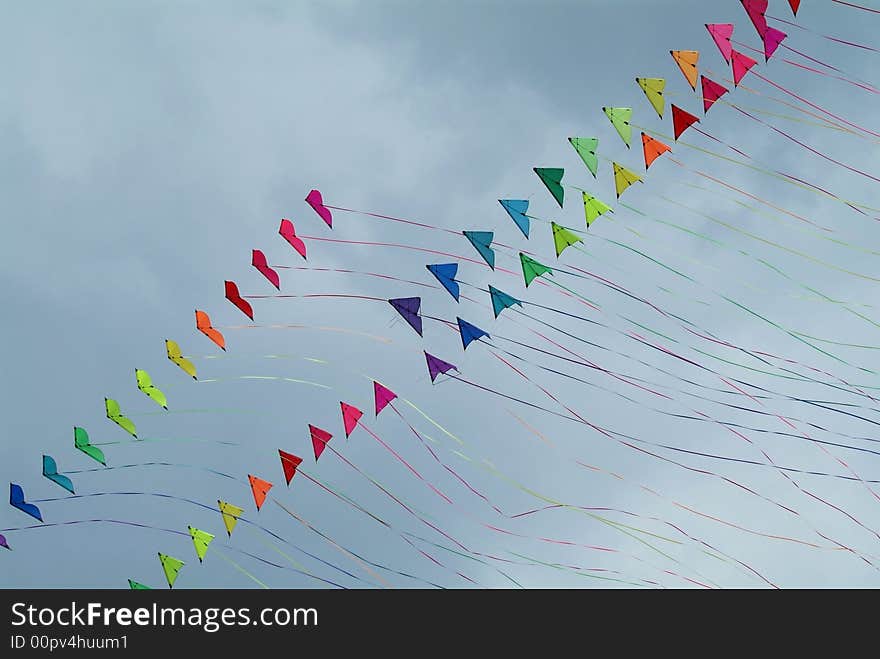 Four strings of colourful stunt kites with long tails on a cloudy sky background. Four strings of colourful stunt kites with long tails on a cloudy sky background