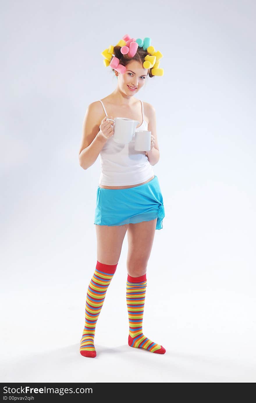 A woman in hair curlers with a teapot and cup. A woman in hair curlers with a teapot and cup