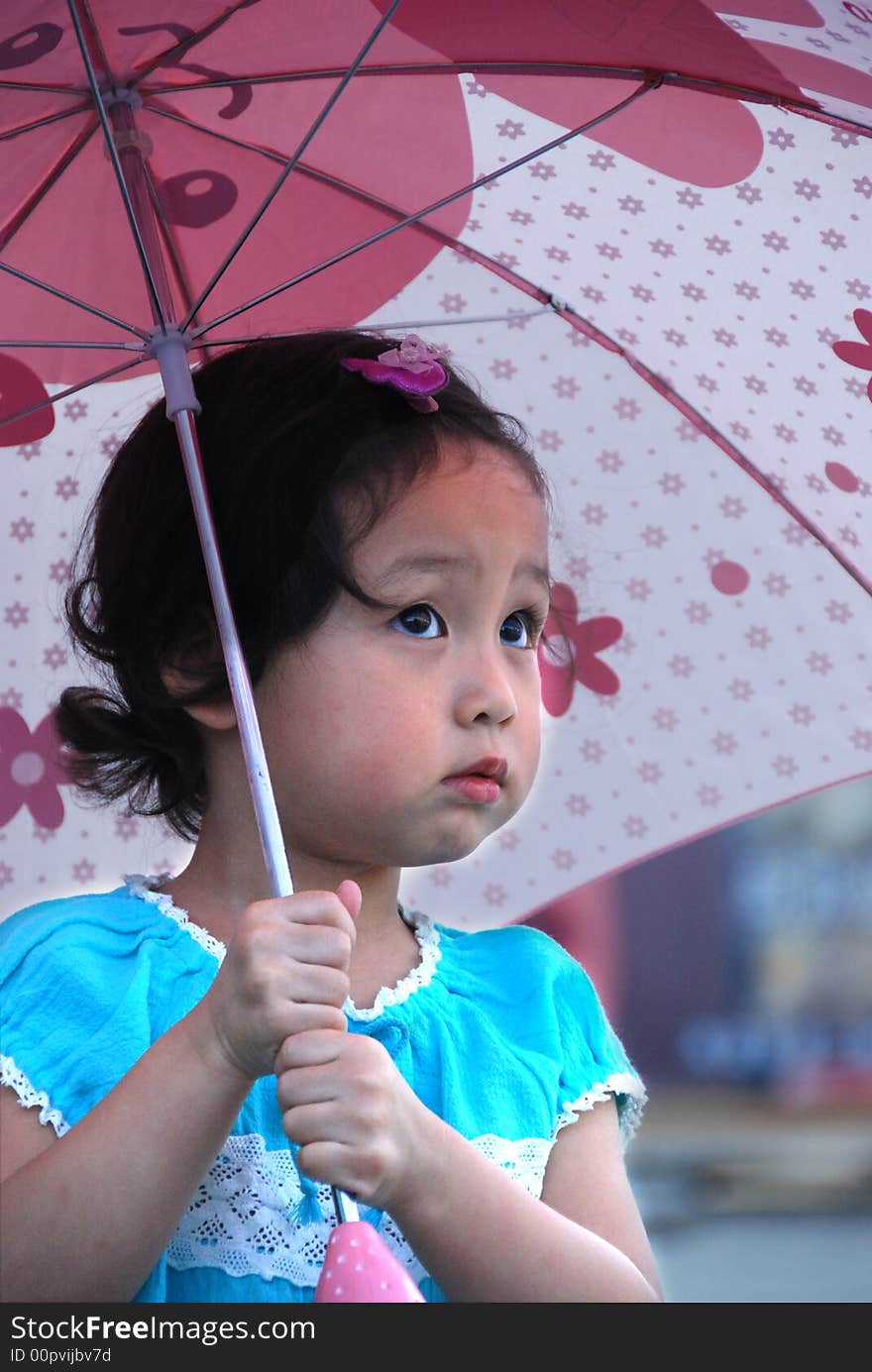 Cute beautiful Chinese young child under umbrella in summer