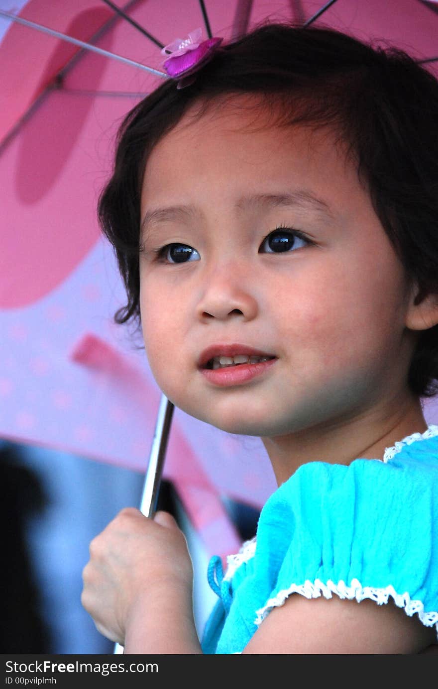 Cute beautiful Chinese young child under umbrella in summer