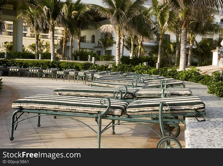 Rows of green and white chaise lounges around a seaside pool