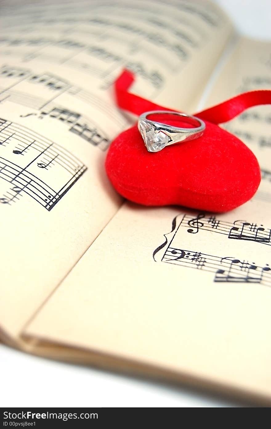 Fabric neart with ring on sheet of music. Fabric neart with ring on sheet of music