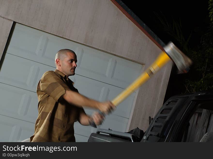 Man chopping a vehicle at night. Can be used to depict a robber trying to break into someones vehicle