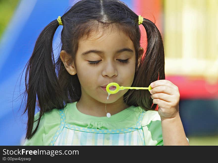 Little Girl blowing bubbles with eyes closed