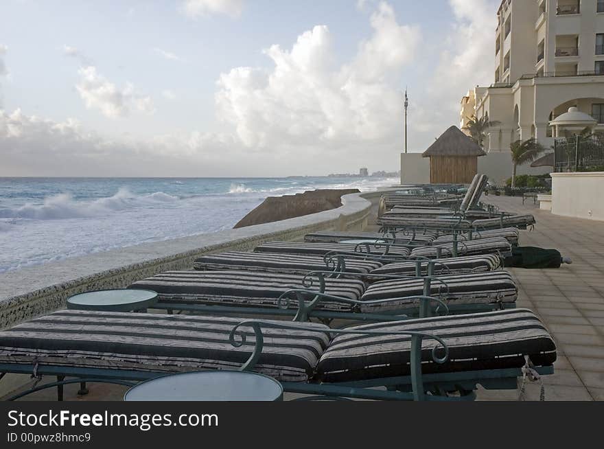 A row of lounge chairs on top of a sea wall at the beach. A row of lounge chairs on top of a sea wall at the beach