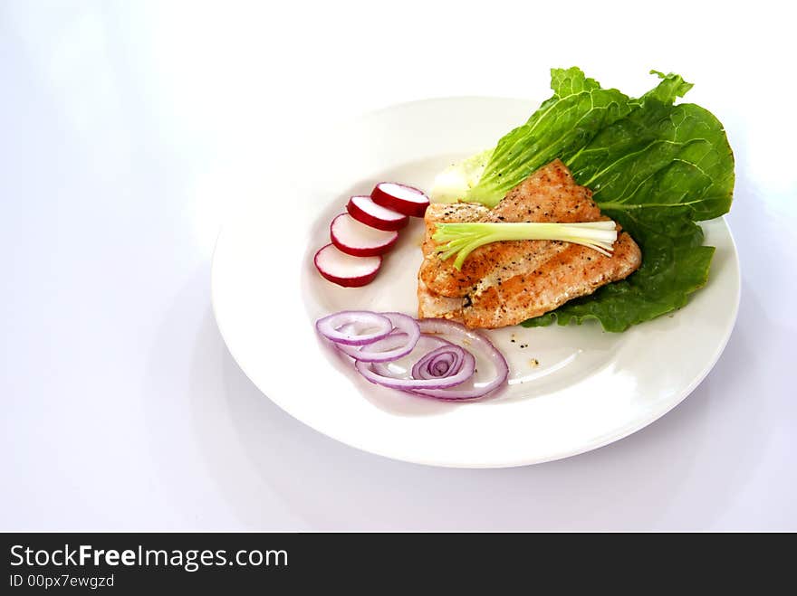 Cooked pink salmon with lettuce leaf, onions, and radish.