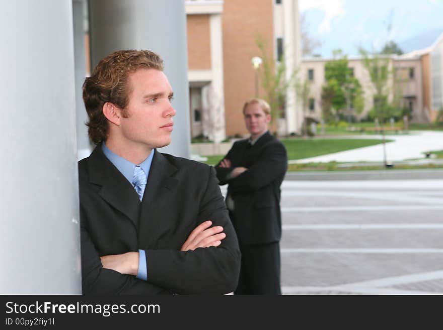 Two businessmen standing in full suits with folded arms. Two businessmen standing in full suits with folded arms