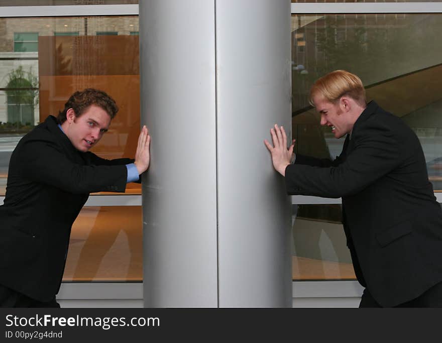 Two businessmen standing and pushing against column from opposite sides. Two businessmen standing and pushing against column from opposite sides