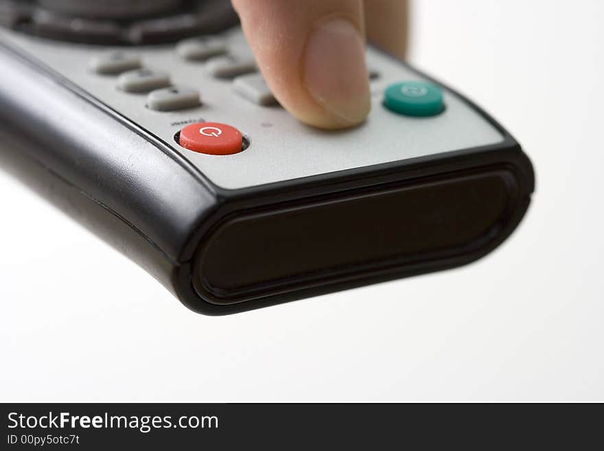 Remote control isolated on white, held in hand with a finger between the Power On and Power Off buttons. Remote control isolated on white, held in hand with a finger between the Power On and Power Off buttons.