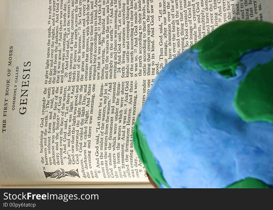 Crude earth globe sitting on an open Bible open to the book of Genesis. Crude earth globe sitting on an open Bible open to the book of Genesis