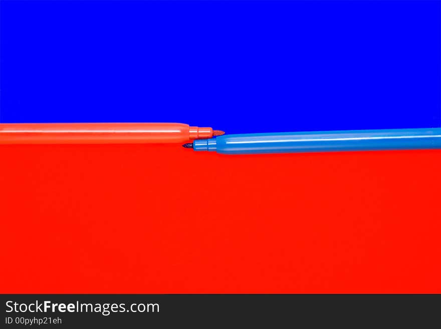 Red and blue felt-tip pens lay on a color background. Red and blue felt-tip pens lay on a color background